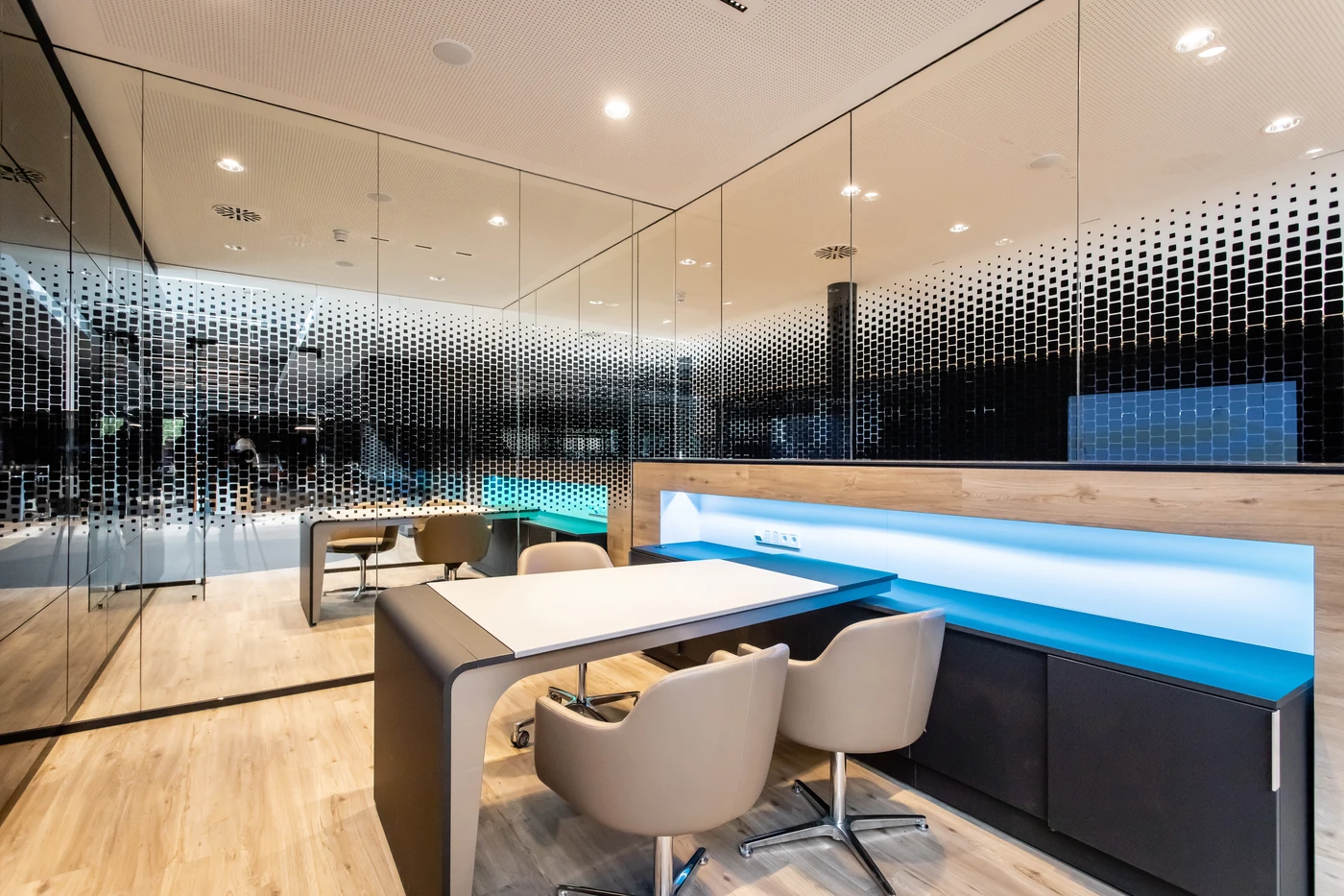 Projekte Ein modernes Büro mit Glaswänden, hellen Holzböden, einem eleganten Schreibtisch, beigen Stühlen und integrierter blauer LED-Beleuchtung. Der von SCHATZ Architektur entworfene Raum wirkt klar, minimalistisch und hell – ein Ergebnis durchdachter Projektentwicklung und Generalplanung, die für eine großzügige Atmosphäre sorgen.