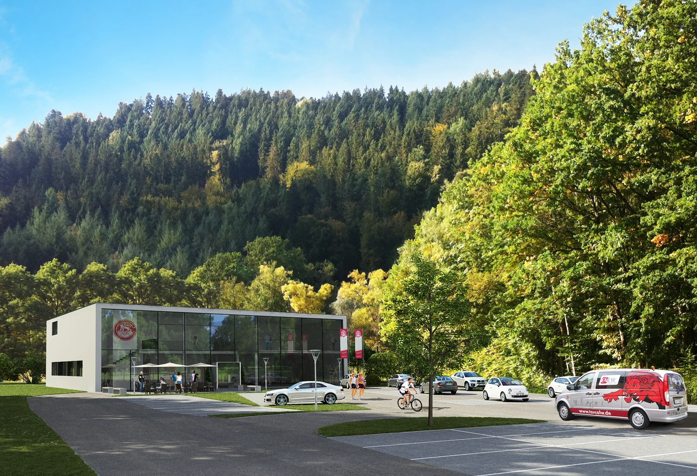 Ein modernes Glasgebäude mit Sitzgelegenheiten im Freien ist umgeben von Autos, Bäumen und bewaldeten Hügeln unter einem strahlend blauen Himmel. Der Ort zeugt von durchdachter Projektentwicklung und Gestaltung und bringt Menschen zusammen, die in der Nähe des Parkplatzes stehen oder mit dem Fahrrad vorbeifahren.